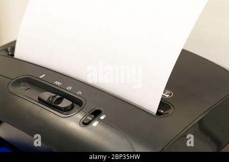 Ein leeres Blatt Papier, das zur Zerstörung aus Sicherheitsgründen in die Aktenvernichter-Maschine eingelegt wurde. Geheimhaltung Konzept. Kopierbereich Stockfoto
