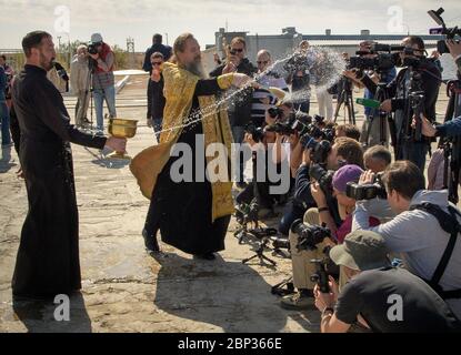 Expedition 61 Sojus-Segen Russisch-orthodoxer Priester Pater Sergei segnet die Sojus-Rakete und Medienvertreter auf der Weltraumrakete Baikonur, Dienstag, 24. September 2019 in Baikonur, Kasachstan. Die Expedition 61-Crew-Mitglieder Jessica Meir von der NASA und Oleg Skripochka von Roskosmos und Raumflugteilnehmer Haszaa Ali Almansoori aus den Vereinigten Arabischen Emiraten starten am 25. September mit der Sojus MS-15-Sonde vom Kosmodrom Baikonur zur Internationalen Raumstation. Stockfoto