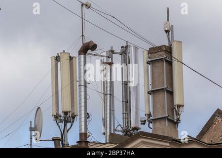 Antennen von Mobilfunk- und Kommunikationssystemen mit blauem Himmel auf dem Dach des Gebäudes. Stockfoto