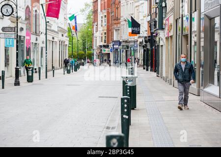 Fußgänger mit Schutzmaske geht durch die verlassene Grafton Street im Stadtzentrum von Dublin, während der Fußabsturz aufgrund der Coronavirus-Pandemie abstürzt. Stockfoto