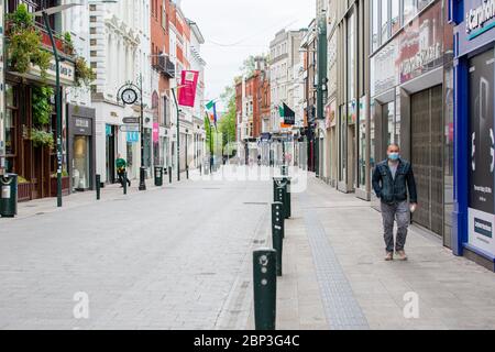 Fußgänger mit Schutzmaske geht durch die verlassene Grafton Street im Stadtzentrum von Dublin, während der Fußabsturz aufgrund der Coronavirus-Pandemie abstürzt. Stockfoto