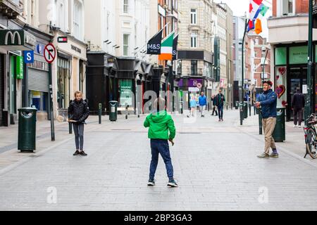 Die Familie spielt auf der verlassenen Grafton Street im Stadtzentrum von Dublin, da Geschäfte und Geschäfte geschlossen bleiben und aufgrund der Covid-19 die Besucherfrequenz sinkt. Stockfoto