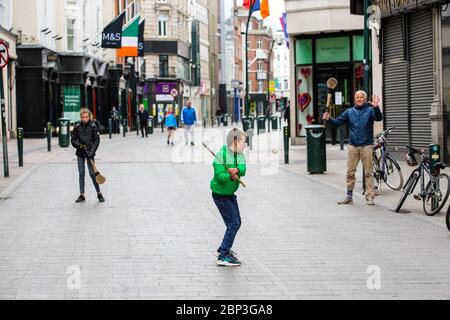 Die Familie spielt auf der verlassenen Grafton Street im Stadtzentrum von Dublin, da Geschäfte und Geschäfte geschlossen bleiben und aufgrund der Covid-19 die Besucherfrequenz sinkt. Stockfoto