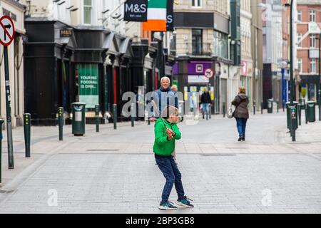 Die Familie spielt auf der verlassenen Grafton Street im Stadtzentrum von Dublin, da Geschäfte und Geschäfte geschlossen bleiben und aufgrund der Covid-19 die Besucherfrequenz sinkt. Stockfoto