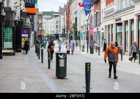 Fußgänger, die durch die ruhige Grafton Street im Stadtzentrum von Dublin gehen, da die Geschäfte geschlossen bleiben und der Fußabsturz aufgrund der Coronavirus-Pandemie abstürzt. Stockfoto