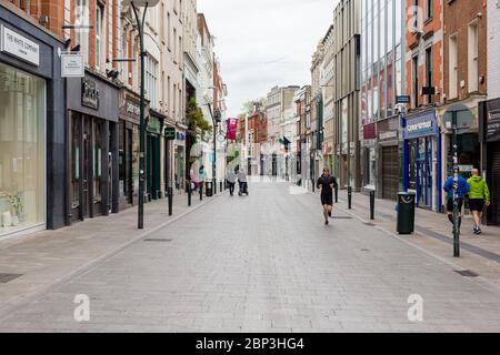 Fußgänger, die durch eine verlassene Grafton Street im Stadtzentrum von Dublin schlendern, da die Geschäfte wegen der Pandemie des Coronavirus geschlossen bleiben. Stockfoto