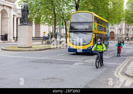 Radfahrer mit Schutzmaske und Dublin Bus durch College Green in Dublin City Centre. Covid-19 Pandemiebeschränkungen. Stockfoto