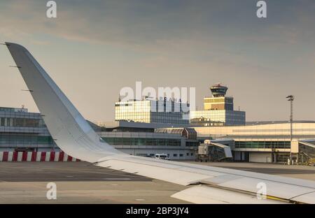 PRAG, TSCHECHISCHE REPUBLIK - AUGUST 2018: Terminal und Kontrollturm am Prager Flughafen, von der Seite eines abfliegenden Flugzeugs aus gesehen. Stockfoto