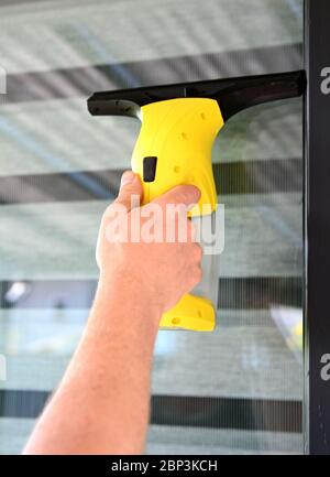 Reinigungsfenster mit kabellosem Elektrostaubsauger. Mann hält und benutzt Staubsauger. Stockfoto