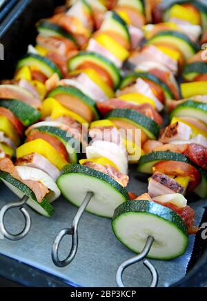 Pfanne voll von Metallspieße mit rohem Schweinefleisch und Gemüse roh zum Backen bereit. Stockfoto