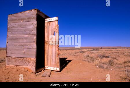 Kleine Holztoilette in ländlicher Antenne gegen klaren blauen Himmel Stockfoto