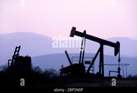 Ein Pumpejack an einem Ölbohrplatz bei Sonnenuntergang in den USA Stockfoto