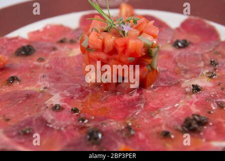 Gericht aus iberischem Rinderfilet Carpaccio mit Tomaten und Olivenöl Stockfoto