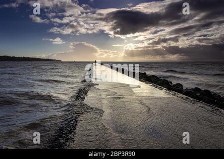 Wasser über dem Weg um den See, West Kirby. Flut und windige Bedingungen. Stockfoto