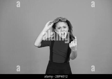 Aufenthalt mit Brille konzentriert. cool aussehende Schüler orange Hintergrund fühlen Wut. hübsche und stilvolle Kind. Strenge kleines Mädchen Schuluniform. Party Brille für Spaß. Kid Mode Konzept. Stockfoto