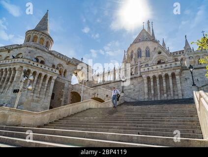 Ein Mann geht die Stufen der Fischerbastei hinunter, eine berühmte Sehenswürdigkeit in Budapest, und trägt eine Maske wegen der COVID-19-Epidemie. Stockfoto