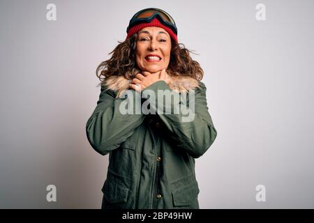 Mittlere Alter Skifahrer Frau trägt Schnee Sportbekleidung und Skibrille über weißem Hintergrund schreien und ersticken, weil schmerzhafte Erwürgen. Gesundheitsproblem. Stockfoto