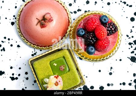 Bunte Kuchen, Mousse, Matcha-Kuchen, garniert mit Beeren Stockfoto