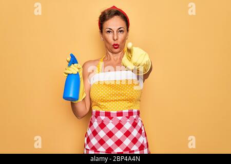 Mittlere Alter Senior Hausfrau Pin-up Frau trägt 50s Stil Retro Kleid Reinigung mit Spray zeigt mit Finger auf die Kamera und zu Ihnen, Handzeichen, Stockfoto