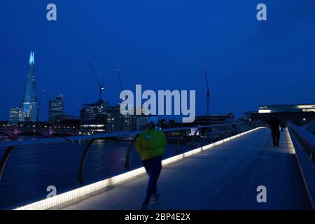 London, Großbritannien, 17. Mai 2020: Menschen gehen und radeln über die Milemmium Bridge, während die Spitze des Shard blau beleuchtet ist und Tate Modern Schilder trägt, die "Danke an Schlüsselarbeiter" sagen, um NHS-Mitarbeiter und andere Pflegekräfte und Schlüsselarbeiter vor Ort zu ehren. Anna Watson/Alamy Live News Stockfoto