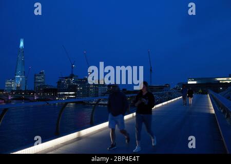 London, Großbritannien, 17. Mai 2020: Menschen gehen und radeln über die Milemmium Bridge, während die Spitze des Shard blau beleuchtet ist und Tate Modern Schilder trägt, die "Danke an Schlüsselarbeiter" sagen, um NHS-Mitarbeiter und andere Pflegekräfte und Schlüsselarbeiter vor Ort zu ehren. Anna Watson/Alamy Live News Stockfoto