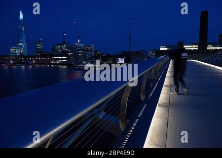 London, Großbritannien, 17. Mai 2020: Menschen gehen und radeln über die Milemmium Bridge, während die Spitze des Shard blau beleuchtet ist und Tate Modern Schilder trägt, die "Danke an Schlüsselarbeiter" sagen, um NHS-Mitarbeiter und andere Pflegekräfte und Schlüsselarbeiter vor Ort zu ehren. Anna Watson/Alamy Live News Stockfoto