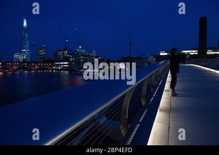 London, Großbritannien, 17. Mai 2020: Menschen gehen und radeln über die Milemmium Bridge, während die Spitze des Shard blau beleuchtet ist und Tate Modern Schilder trägt, die "Danke an Schlüsselarbeiter" sagen, um NHS-Mitarbeiter und andere Pflegekräfte und Schlüsselarbeiter vor Ort zu ehren. Anna Watson/Alamy Live News Stockfoto