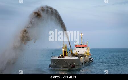 Bagger Sospan Dau pumpt Schindel zurück zum Strand Stockfoto