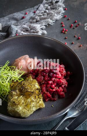 Teer-Teer aus Rindfleisch mit getrockneten Preiselbeeren und Daikon auf grauem Hintergrund. Löffel, Gabel und graue Tischdecke Stockfoto