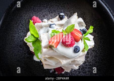 Dessert Pavlova mit Erdbeere, Himbeere, Minze, Heidelbeere auf grauem Hintergrund. Draufsicht Stockfoto