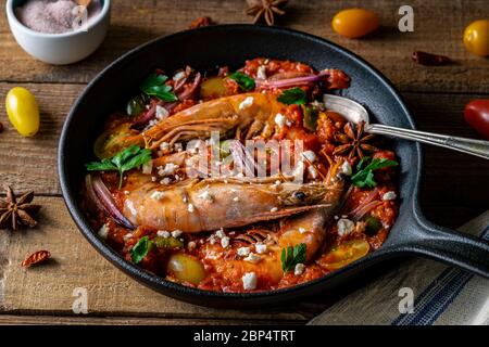 Garnelen in Gusseisenpfanne mit roter Tomatensoße mit Petersilie und Feta-Käse gekocht. Stockfoto