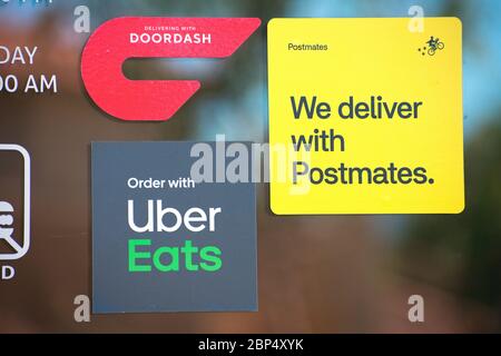 DoorDash, Postmates und Uber isst Aufkleber Aufkleber Aufkleber auf einer Restauranttür Werbung verfügbaren Lieferservice durch Online-Lebensmittel-Bestellunternehmen - Stockfoto