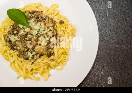 Schöne hausgemachte Pasta mit Fleischsoße und Gorgonzola Käse auf schwarzem Stein Hintergrund. Stockfoto