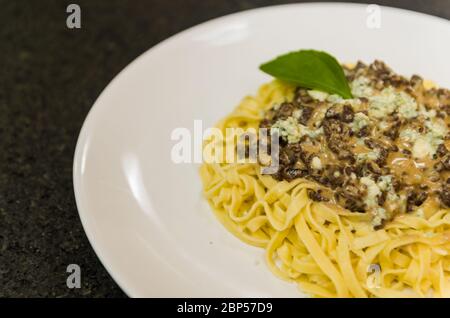 Schöne hausgemachte Pasta mit Fleischsoße und Gorgonzola Käse auf schwarzem Stein Hintergrund. Stockfoto