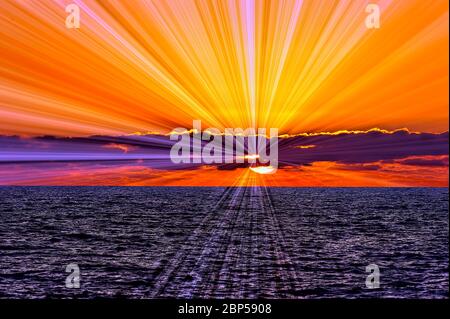 Ein wunderschöner inspirierender Sonnenuntergang am Ozean mit Sonnenstrahlen und Licht, das von der Sonne ausgeht Stockfoto