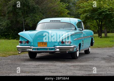 Turquoise 1958 Chevrolet Impala Coupé mit Heckschürze gegen Bäume Heckansicht in Dreiviertelansicht Stockfoto