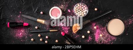 Professionelles Make-up-Panorama auf dunklem Hintergrund. Pinsel, Lippenstift und andere Produkte, eine flache Lage Stockfoto