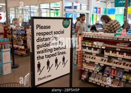 Das Schild am Kassenbereich in A Whole Foods Market erinnert die Käufer daran, die Richtlinien zur sozialen Distanzierung während der COVID-19-Pandemie am 15. 5. 2020 zu beachten. Stockfoto