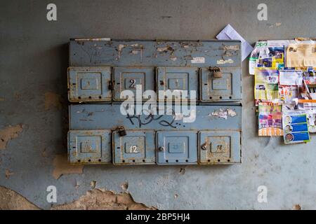 Ein Satz alter, grauer, metallener, Stahl, schließende, an der Wand montierter Briefkästen in einem alten kommunistischen Apartmentgebäude. In Vilnius, Litauen. Stockfoto