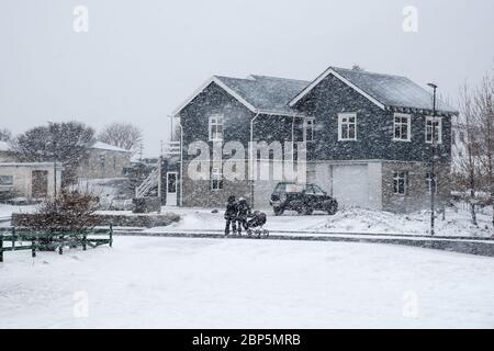 Unerkannte Familie mit Kind, das draußen während des schweren Schneesturms im Dorf Vik in Island herumläuft Stockfoto