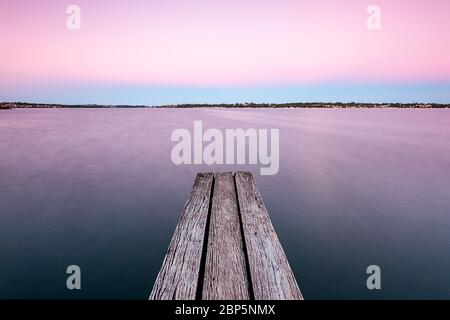 Alte Holzplanken auf einem Steg über dem Fluss bei Sonnenaufgang Stockfoto