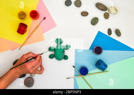 Schritt für Schritt eine Steinschildkröte auf einem Stein malen. Kinder Kunstprojekt. DIY-Konzept. Schritt für Schritt 3 Fotoanleitung.Ansicht von oben. Arbeiten mit c Stockfoto