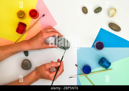 Wie man einen Regenbogen auf einem Stein Schritt für Schritt zeichnet. Kinder Kunstprojekt. DIY-Konzept. Schritt für Schritt Fotoanleitung.Ansicht von oben. Mit Kindern arbeiten A Stockfoto