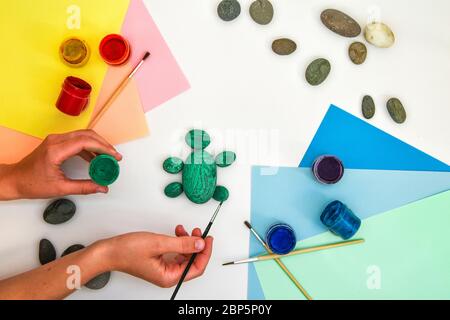 Schritt für Schritt eine Steinschildkröte auf einem Stein malen. Kinder Kunstprojekt. DIY-Konzept. Schritt für Schritt 3 Fotoanleitung.Ansicht von oben. Arbeiten mit c Stockfoto