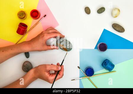 Wie man einen Regenbogen auf einem Stein Schritt für Schritt zeichnet. Kinder Kunstprojekt. DIY-Konzept. Schritt für Schritt Fotoanleitung.Ansicht von oben. Mit Kindern arbeiten A Stockfoto