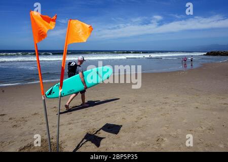 Los Angeles, Kalifornien, USA. März 2019. Ein Surfer geht am Strand entlang, während die Menschen in Venice Beach soziale Distanz aufrechterhalten.Los Angeles County hat seine Strände für den aktiven Gebrauch wiedereröffnet, während die Menschen Gesichtsmasken tragen und soziale Distanz aufrechterhalten müssen, während der Landkreis versucht, COVID-19-Infektionen zu reduzieren. Kredit: Ronen Tivony/SOPA Images/ZUMA Wire/Alamy Live News Stockfoto