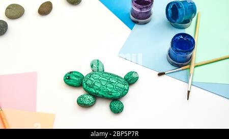 Schritt für Schritt eine Steinschildkröte auf einem Stein malen. Kinder Kunstprojekt. DIY-Konzept. Schritt für Schritt 6 Fotoanleitung. Blick von oben. Arbeiten mit Stockfoto