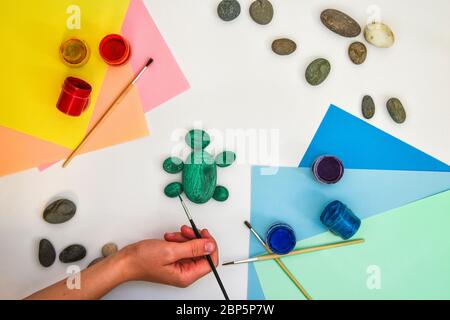 Schritt für Schritt eine Steinschildkröte auf einem Stein malen. Kinder Kunstprojekt. DIY-Konzept. Schritt für Schritt 3 Fotoanleitung.Ansicht von oben. Arbeiten mit c Stockfoto
