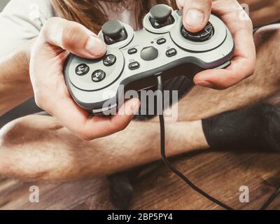 Spiele Konzept. Teil Körper Mann mit Joystick spielen Spiel auf Konsole Playstation. Männliche Hände halten grau Pad. Stockfoto