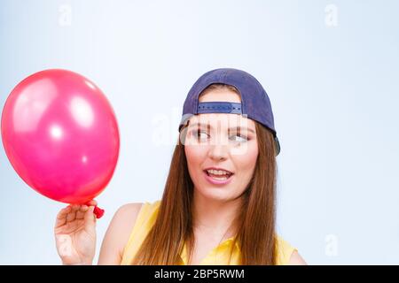 Junges Mädchen, lustig dumme Gesichter. Junge trendige Frau in Jeans cap halten roten Ballon. Stockfoto